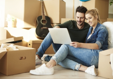 Couple with laptop around cardboard boxes